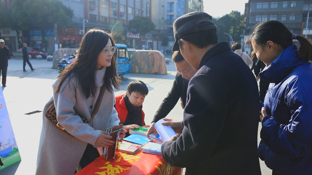 图为工作人员正在为过往群众发放宣传材料，并答疑解惑。.jpg