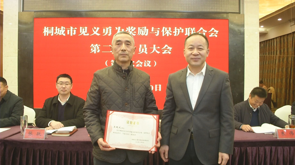 图为市委常委、政法委书记为新当选的桐城市第二届见义勇为余保护联合会会长吴绳武颁发任命证书.jpg