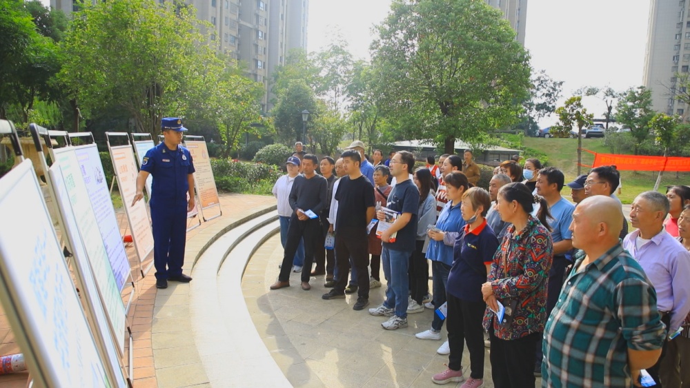 图为消防员正在结合展板为小区居民讲解防灾减灾自救知识.jpg